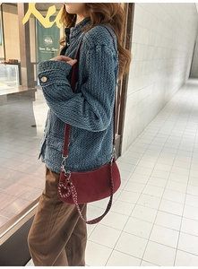 Close-up of wine red matte crossbody bag with silver studs and heart-shaped charm detail