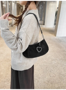 Detailed view of black retro underarm bag featuring heart-shaped rivet pendant and strap