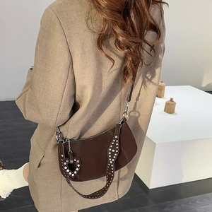 Dark brown crescent shoulder bag with silver rivet strap and heart pendant detail