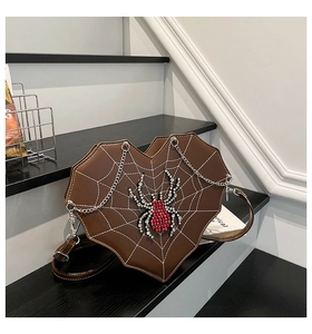 Detail of gothic heart-shaped spider web bag with a red rhinestone spider and silver chain