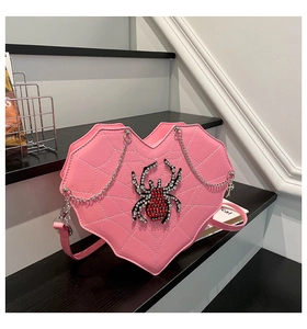 Detail of pink heart-shaped crossbody bag with spider web stitching and rhinestone spider
