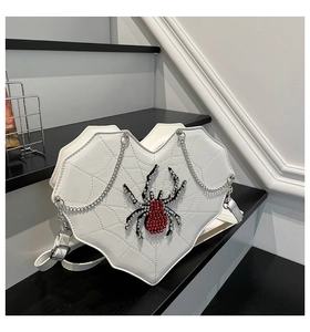 Detail of white heart-shaped bag with spider web stitching and rhinestone spider ornament