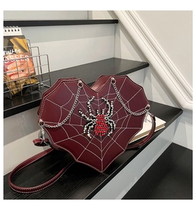 Detail of burgundy heart-shaped crossbody bag with spider web and rhinestone ornament