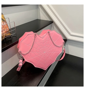 Detail of pink heart bag with white spider web stitching and silver cross charm