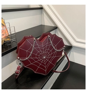 Detail of burgundy heart-shaped crossbody bag with white spider web embroidery and silver chain