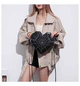 Macro detail of heart-shaped crossbody bag with white spider web stitching and silver chain