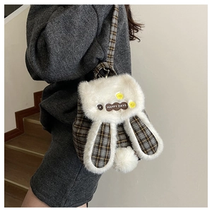Détail du sac à dos en peluche à carreaux avec oreilles en fourrure et patch coeur