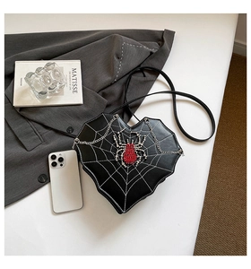 Flat lay of heart shaped crossbody bag with spider web print and rhinestone spider detail