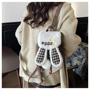Détail d'un sac à dos en peluche lapin avec de longues oreilles et un pompon moelleux