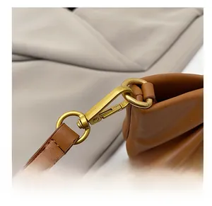 Detail of vintage gold metal hook and fine stitching on a brown leather evening bag