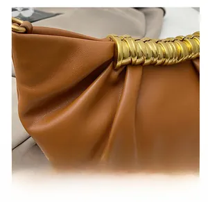 Close-up of brown pleated leather clutch bag with elegant golden wave metal hardware details