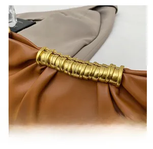 Detail of a brown leather pleated clutch with elegant gold ring metal decoration
