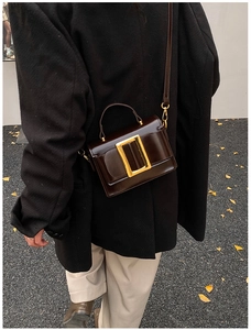 Détail d'un sac bandoulière en cuir marron foncé doté d'une boucle dorée classique