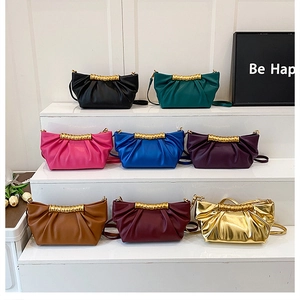 Detailed view of ruched leather clutch bags in eight vibrant colors with gold ring accents