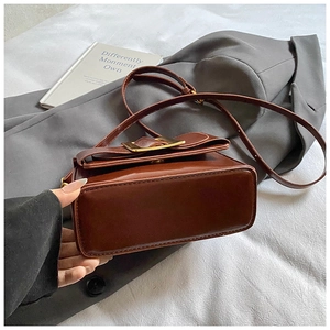 Détail du sac à main en cuir verni marron avec boucle carrée dorée et rabat chic