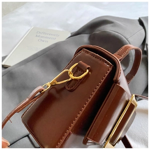 Détail d'un sac bandoulière en cuir marron avec boucle dorée et coutures précises