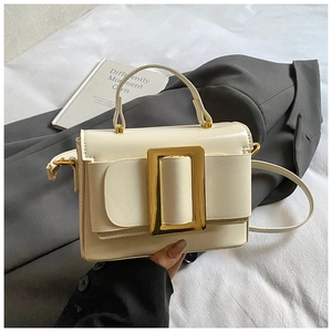 Détail du sac bandoulière minimaliste en cuir beige avec boucle de ceinture dorée