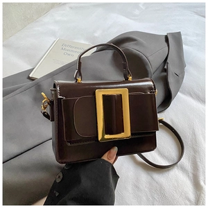 Détail du sac bandoulière marron foncé avec boucle dorée et finition en cuir brillant
