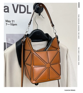 Detailed view of geometric patchwork bucket bag with silver zipper and leather shoulder strap