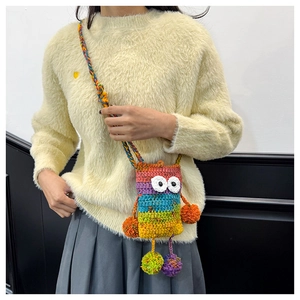 Dettaglio di una borsa a tracolla mostro in maglia colorata con occhi grandi e pompon