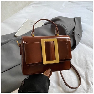 Détail d'un sac à main en cuir marron avec boucle carrée dorée et poignée supérieure