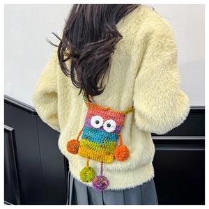 Dettaglio di una borsa a gufo all'uncinetto fatta a mano con filato colorato e pompon decorativi
