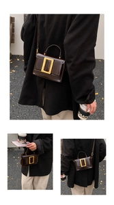 Détail d'un sac carré en cuir verni marron chocolat avec une grande boucle dorée