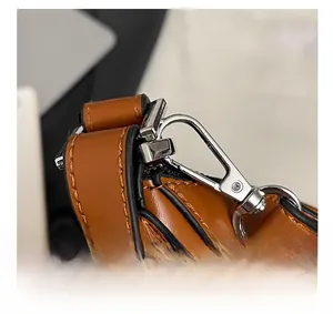 Detail shot of silver metal hardware and fine stitching on the brown leather bucket bag
