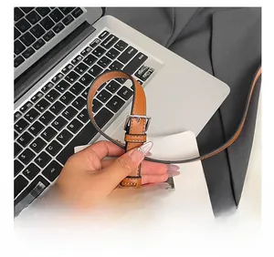 Detail of adjustable brown faux leather shoulder strap with silver metal buckle on bucket bag