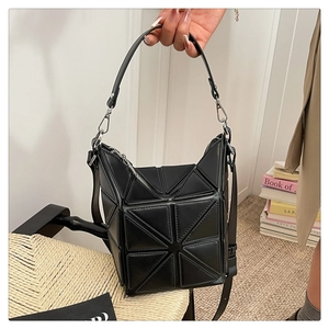 Detail of black geometric patchwork bucket bag with silver hardware and adjustable strap