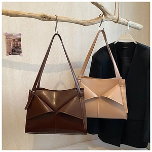 Dettaglio di borse tote con pieghe geometriche in caffè scuro e beige su un ramo