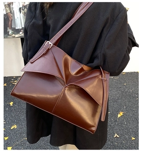 Dettaglio di una borsa a tracolla vintage marrone scuro con design geometrico a busta chiusa