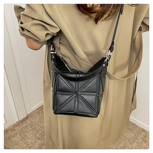 Detail of geometric patchwork black bucket bag with adjustable shoulder strap