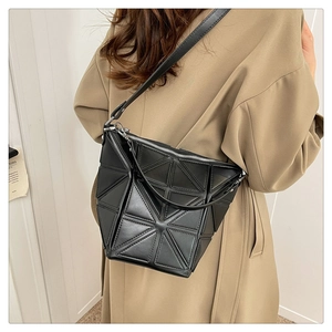 Detailed view of black geometric triangle bag with long leather strap on a model