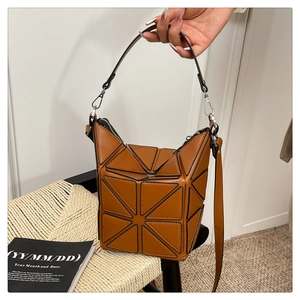Detail view of brown geometric patchwork bucket bag with silver hardware and dual straps