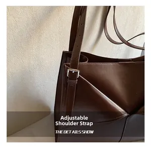 Dettaglio tracolla regolabile con fibbia argentata su borsa tote in pelle marrone