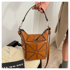 Detail of a brown geometric puzzle bucket bag with adjustable strap in a lifestyle setting