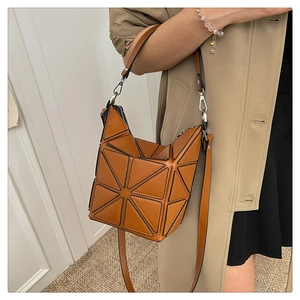 Detailed shot of brown geometric bucket bag with adjustable crossbody strap and top handle