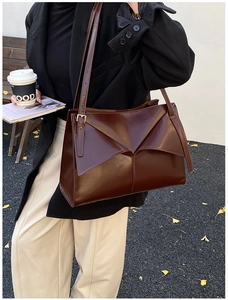 Dettaglio di una borsa tote grande marrone con design geometrico pieghevole in pelle