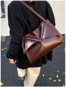 Dettaglio della borsa tote in vernice marrone scuro con pieghe geometriche lucide