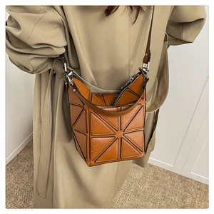 Detail of geometric bucket bag featuring caramel triangular panels and leather strap