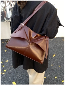 Dettaglio borsa tote in pelle marrone scuro con design geometrico e tracolla regolabile