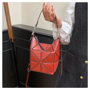 Macro detail of red geometric paneled bucket bag with silver hardware and shoulder strap