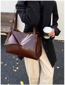 Dettaglio borsa tote in pelle marrone con pieghe geometriche e sottili spalline doppie