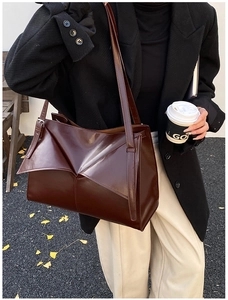 Dettaglio della borsa tote in pelle marrone scuro con pieghe geometriche e finitura