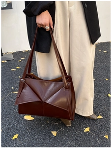 Borsa tote marrone scuro con pieghe geometriche mostrata in un look street style autunnale