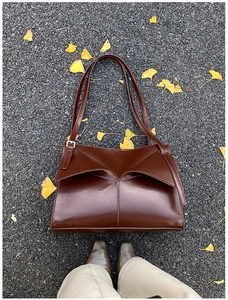Dettaglio della borsa tote in pelle marrone scuro con patta geometrica su sfondo autunnale