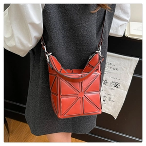 Detail of orange geometric patchwork bucket bag with adjustable strap on model