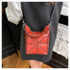Close-up of red geometric bucket bag featuring 3D triangular panel design and fine leather strap