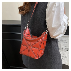 Close-up of red geometric bucket bag featuring glossy triangular panels and silver hardware